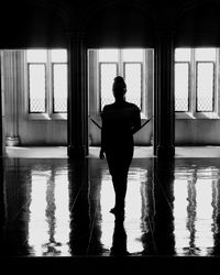 Rear view of silhouette man standing by window