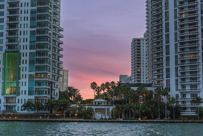 Illuminated buildings against sky at sunset