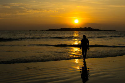 Silhouette man standing on beach during sunset