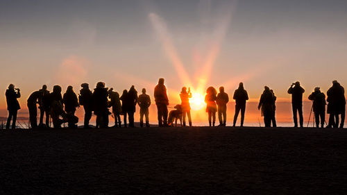 Silhouette people standing on beach during sunset