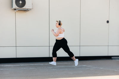 Full length of woman standing against wall