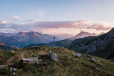 Scenic view of mountains with a cross against sky during sunset in kleinwalsertal