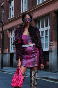 Young woman wearing sunglasses standing on street in city