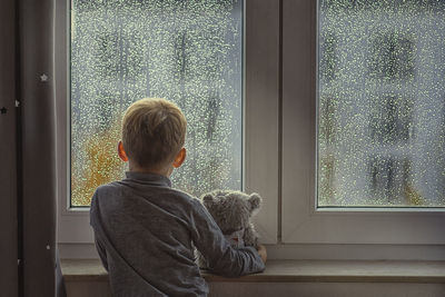 Rear view of man looking through window