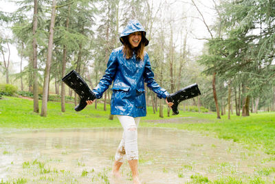 Happy woman with rubber boots walking in puddle