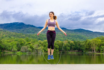 Full length of woman standing against lake