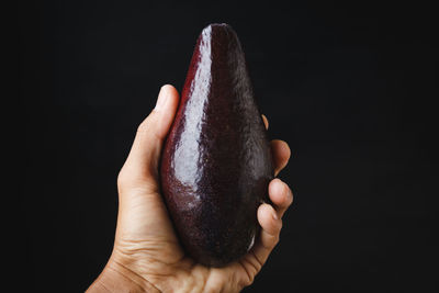Close-up of hand holding ice cream against black background