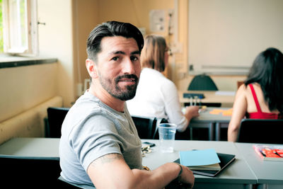 Portrait of confident mid adult man sitting in language school