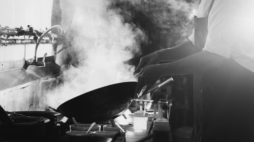 Chef stir fry busy cooking in kitchen. chef stir fry the food in a frying pan, smoke and splatter 