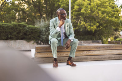 Mature businessman sitting on bench in park