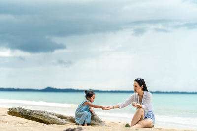 Friends on sea shore against sky