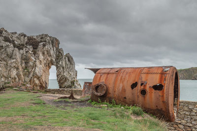 Old rusty metallic structure on land against sky