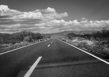 Road through desert against cloudy sky