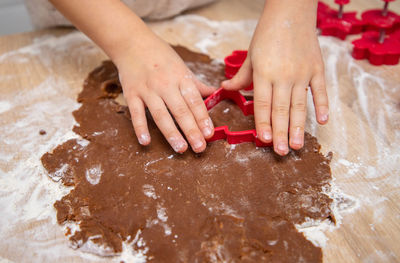 Child making christmas cookies from gingerbread dough and cookie cutters