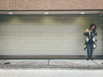 Full length of woman standing against wall