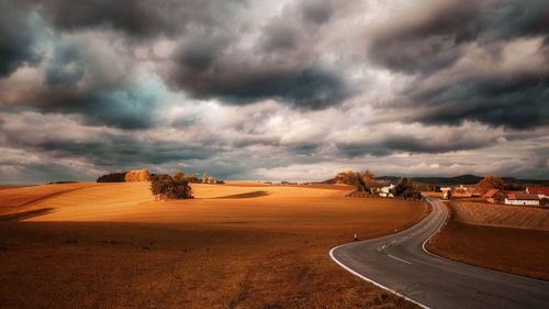 Road in desert against cloudy sky