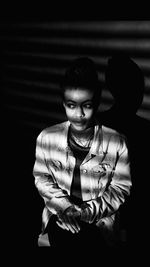 Portrait of young woman sitting in a dark room