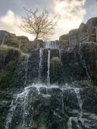 View of waterfall against cloudy sky