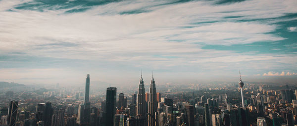 Panoramic view of buildings in city against cloudy sky