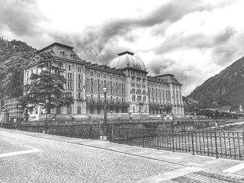 Building by street against cloudy sky