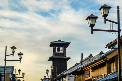 Low angle view of street light by building against sky