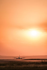 Airplane on runway against sky during sunset