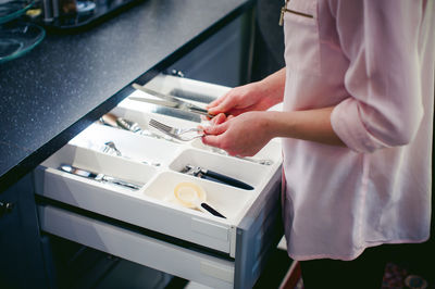 Midsection of man holding eating utensils at kitchen