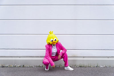 Full length of a boy with toy while standing against pink wall