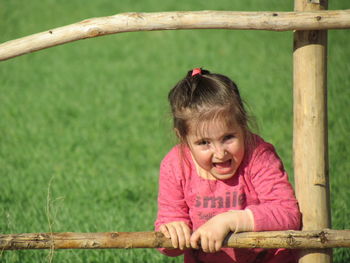 Close-up of girl playing by wooden fence