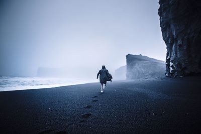 Man running at beach against sky