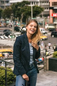 Young woman smiling while standing on street in city