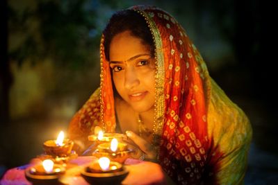 Portrait of smiling woman with illuminated oil lamps 