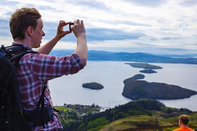 Man photographing sea against sky