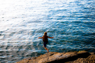 Rear view of boy jumping in sea