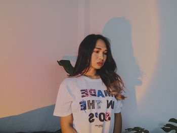 Portrait of young woman standing against wall