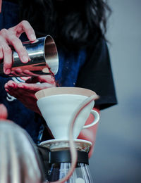 Midsection of woman pouring coffee in cup