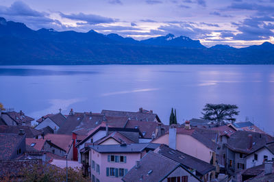 Houses by lake against sky in town