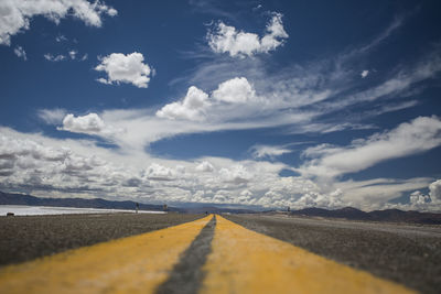 Surface level of empty road against cloudy sky