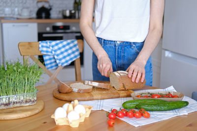 Young healthy woman cuts into pieces whole unleavened bread for breakfast or snack