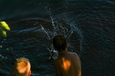 Rear view of shirtless man swimming in sea