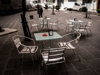 Close-up of chairs and table at sidewalk cafe