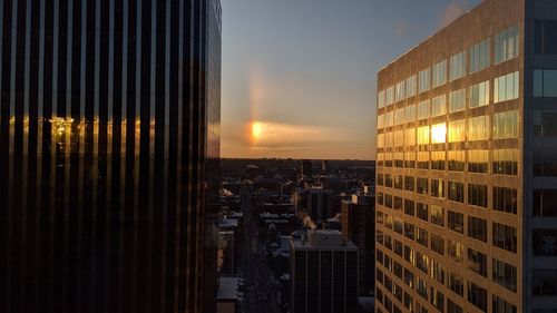 Modern buildings in city against sky during sunset