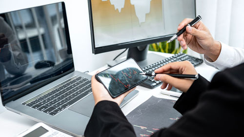 Midsection of man using mobile phone in office