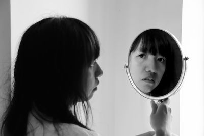 Portrait of young woman with reflection on mirror