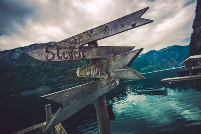 Directional signs against lake during sunset