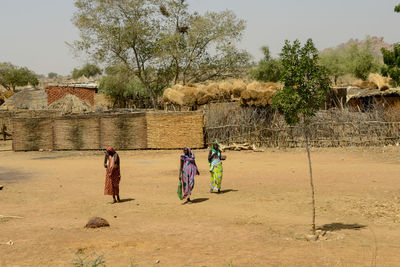 People on field by trees against sky