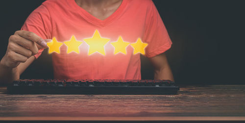 Midsection of person holding illuminated lighting equipment on table