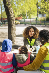 Smiling woman talking with female friend sitting by children at table