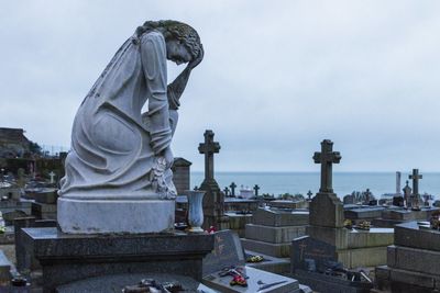 Statue in city against cloudy sky