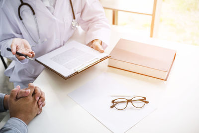 High angle view of doctor talking to patient at desk in hospital